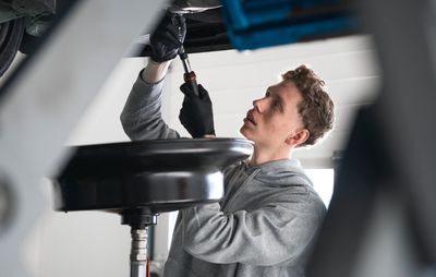 Mécanicien intervenant sous une voiture dans un atelier automobile