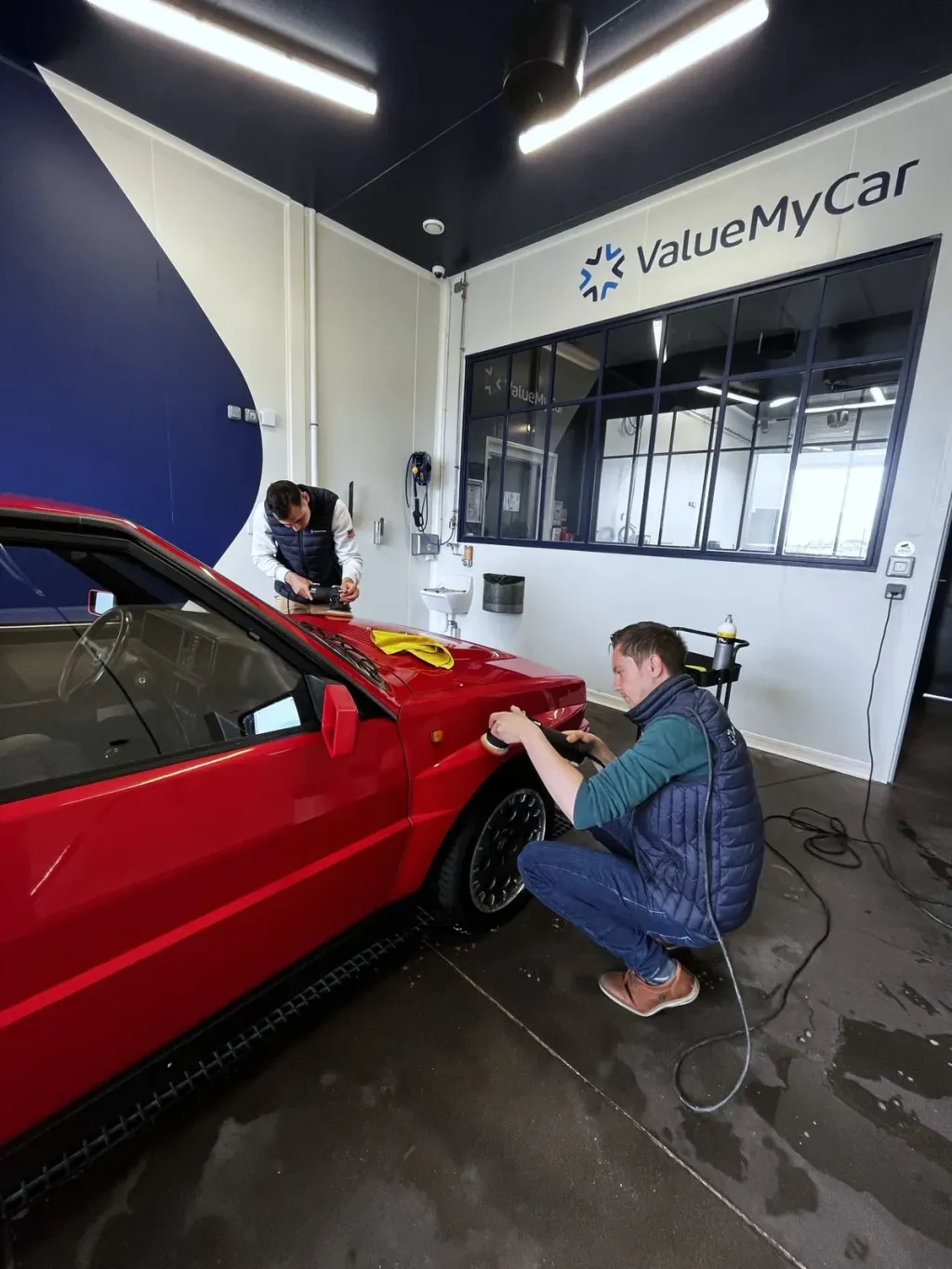 Polissage de la carrosserie d'une Lancia Delta Integrale rouge dans le box detailing