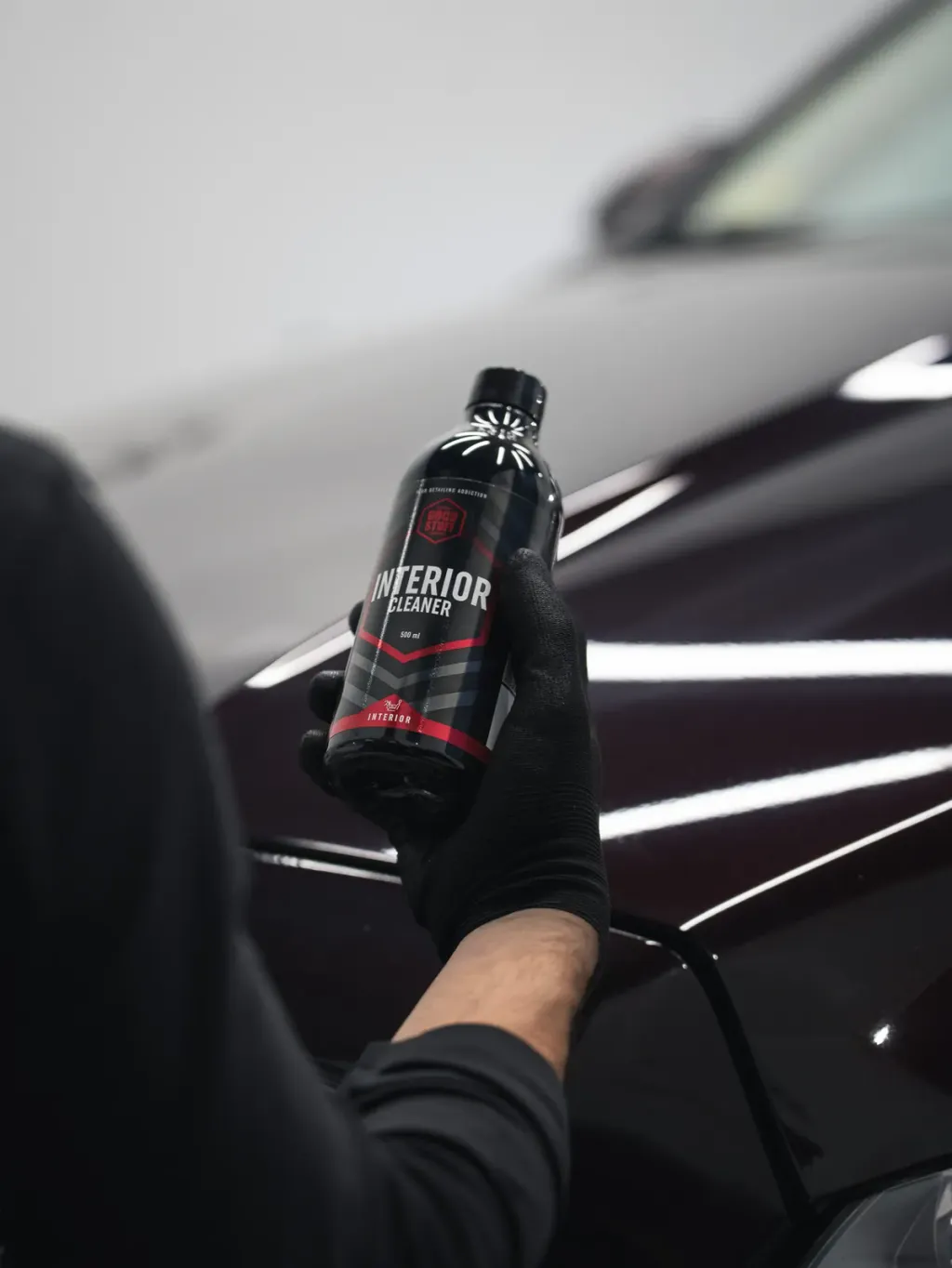 Produit de finition tenu au-dessus d'une carrosserie noire