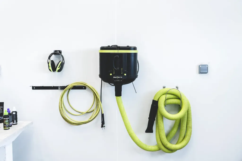 Aspirateur, soufflette et casque anti-bruit rangés au mur