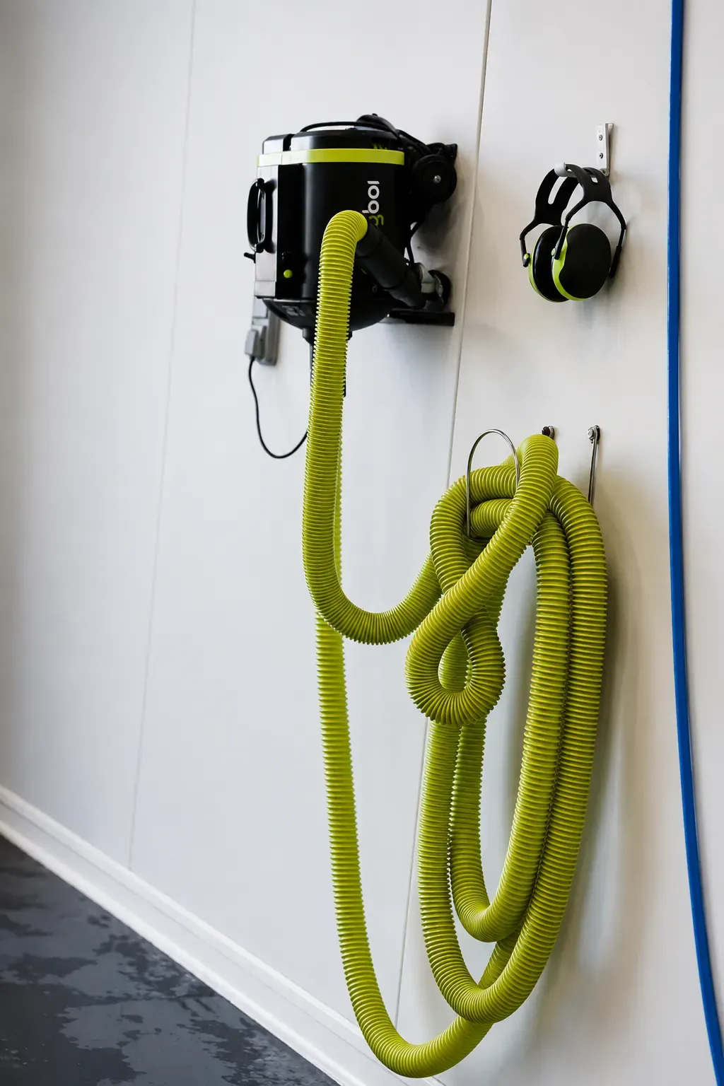 Aspirateur et soufflette suspendus au mur du box lavage